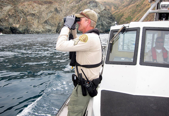 Deputy on a boat using binoculars