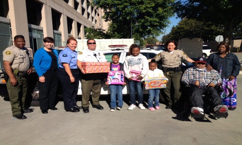 Picture of Rancho Los Amigos Sheriff Personnel giving a Food Box and Gifts to a Family.