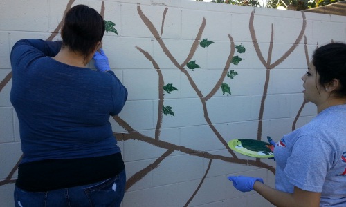 parents and children painting a graffiti covered wall