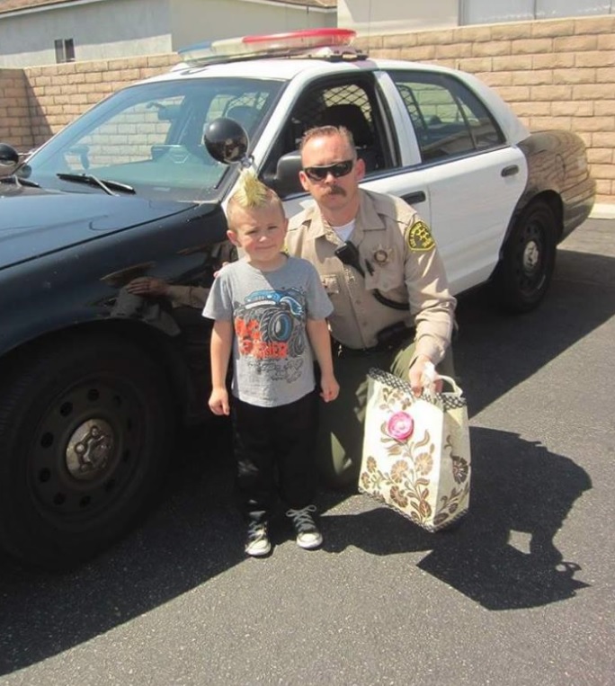 Young man with deputy next to a police car