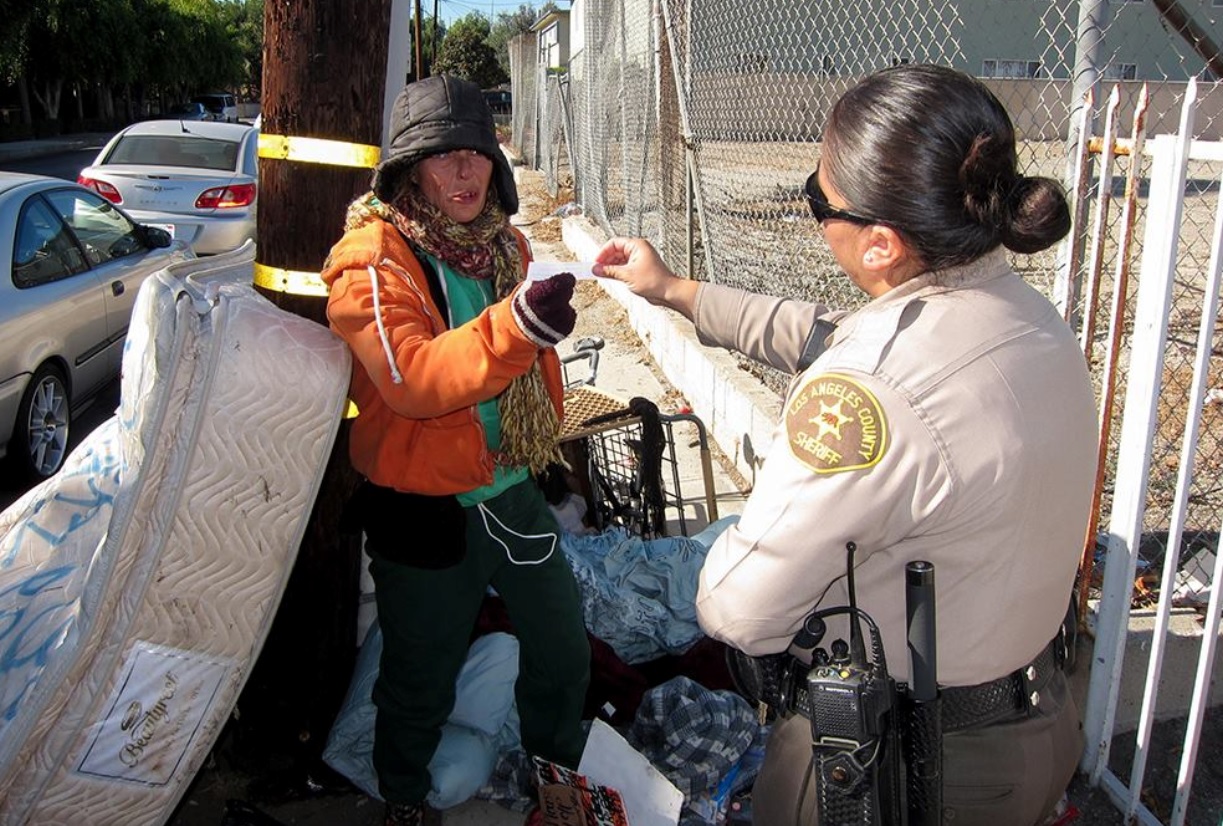 Deputy handing a homeless woman shelter information